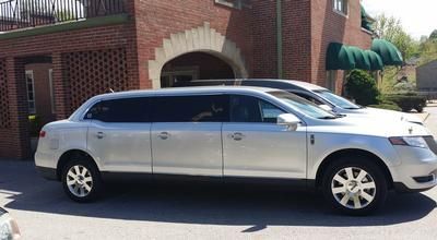 Silver sedan parked on a residential street beside a brick house