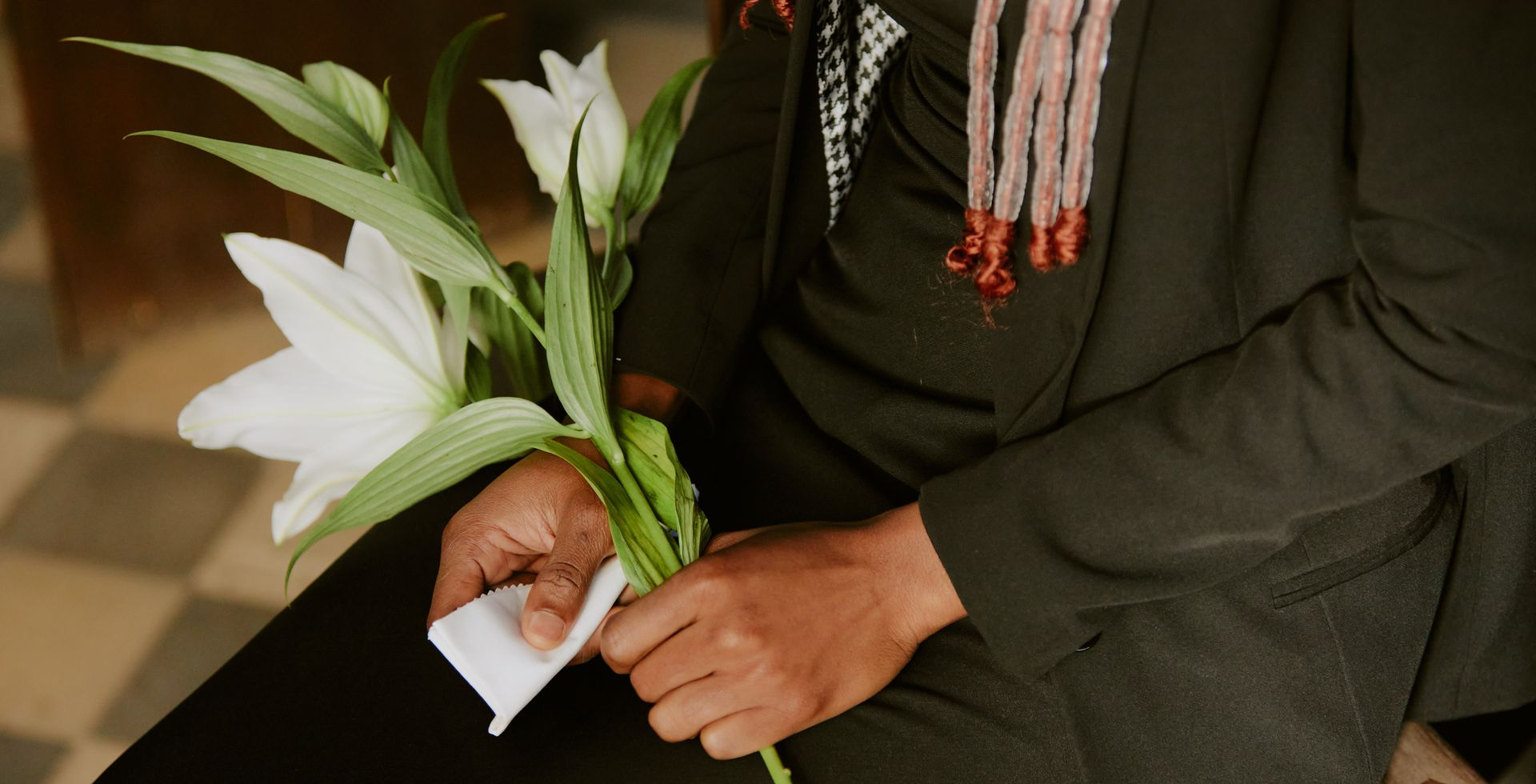 A woman in a black dress is holding a white flower in her hands.