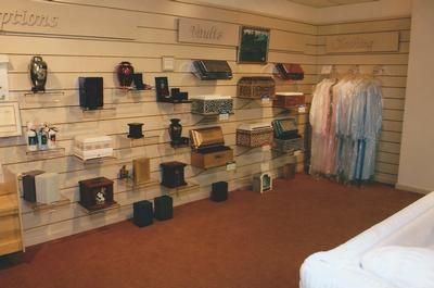 Handbag display on slatwall shelves in a boutique, with hanging clothing on the right.