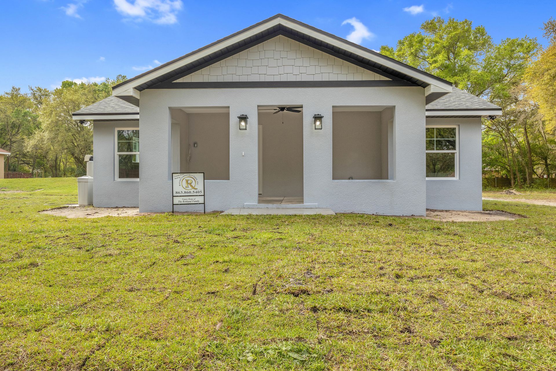 A small white house is sitting in the middle of a lush green field.