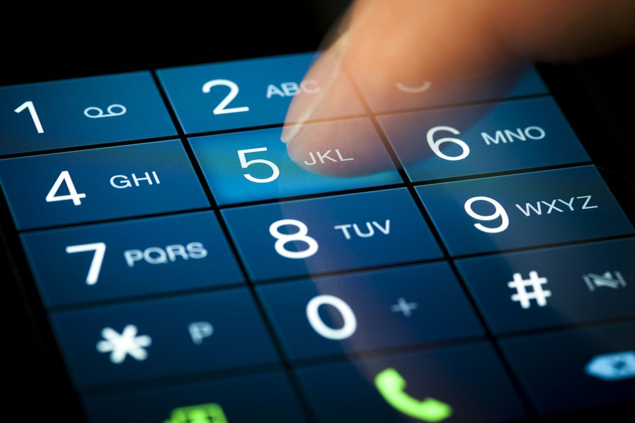 A person is typing a phone number on a cell phone