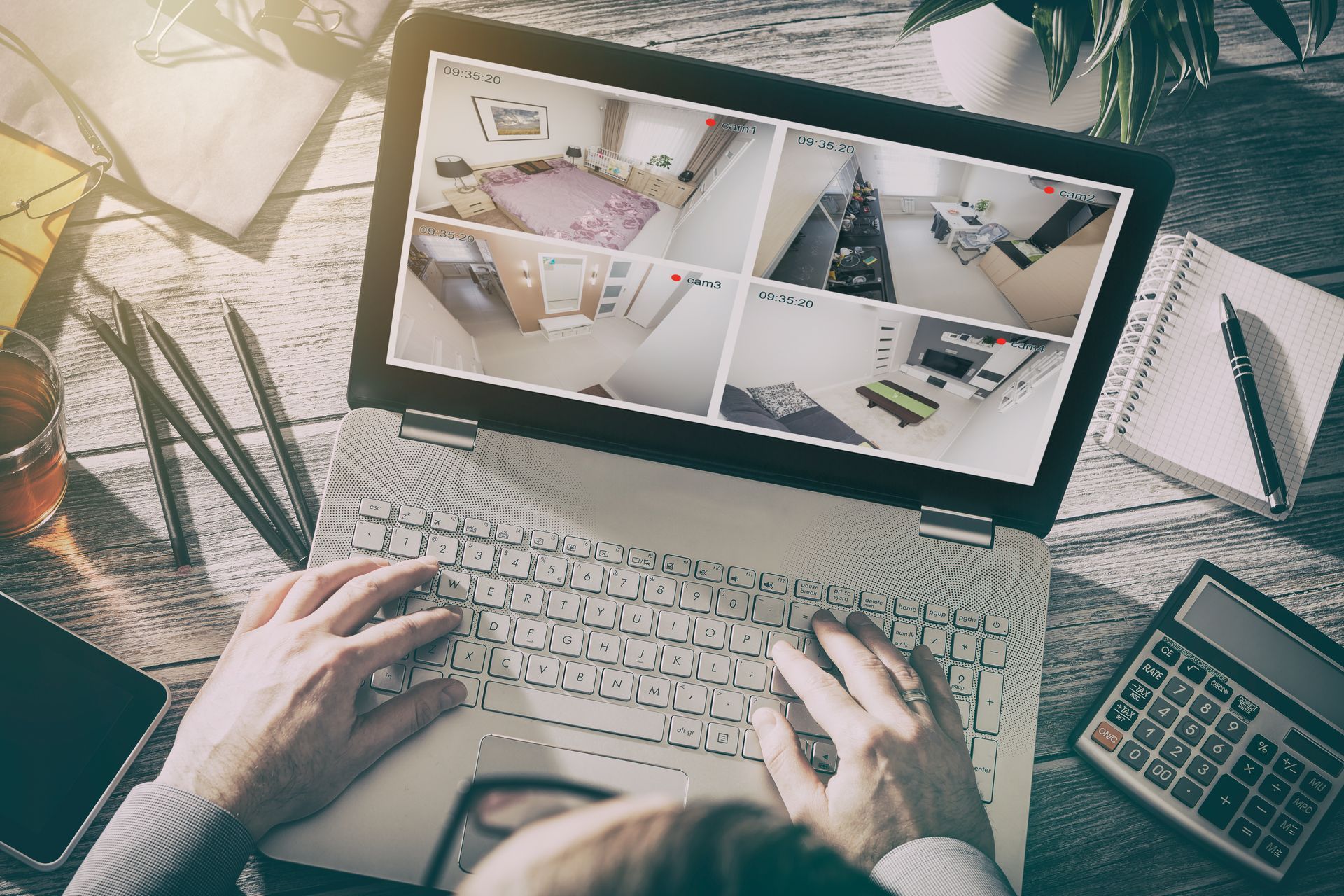 Hands typing on a laptop showing design layouts, with a calculator and coffee on a desk.