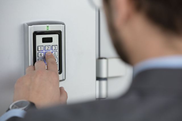 Person entering a code on a wall-mounted electronic keypad