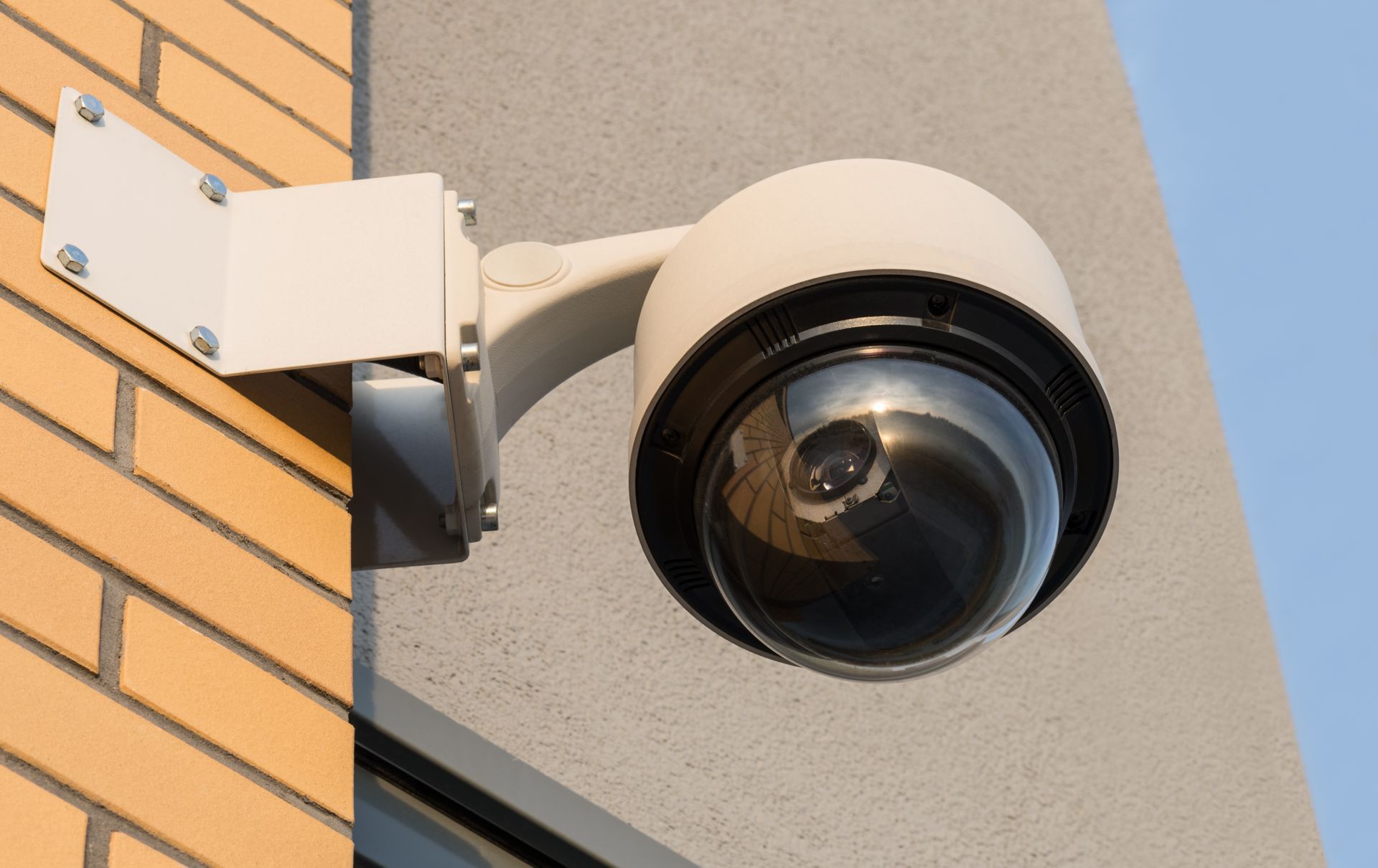 Outdoor security camera mounted on a building corner above a brick wall