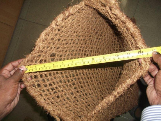 Hands measuring a woven basket with a yellow tape measure.