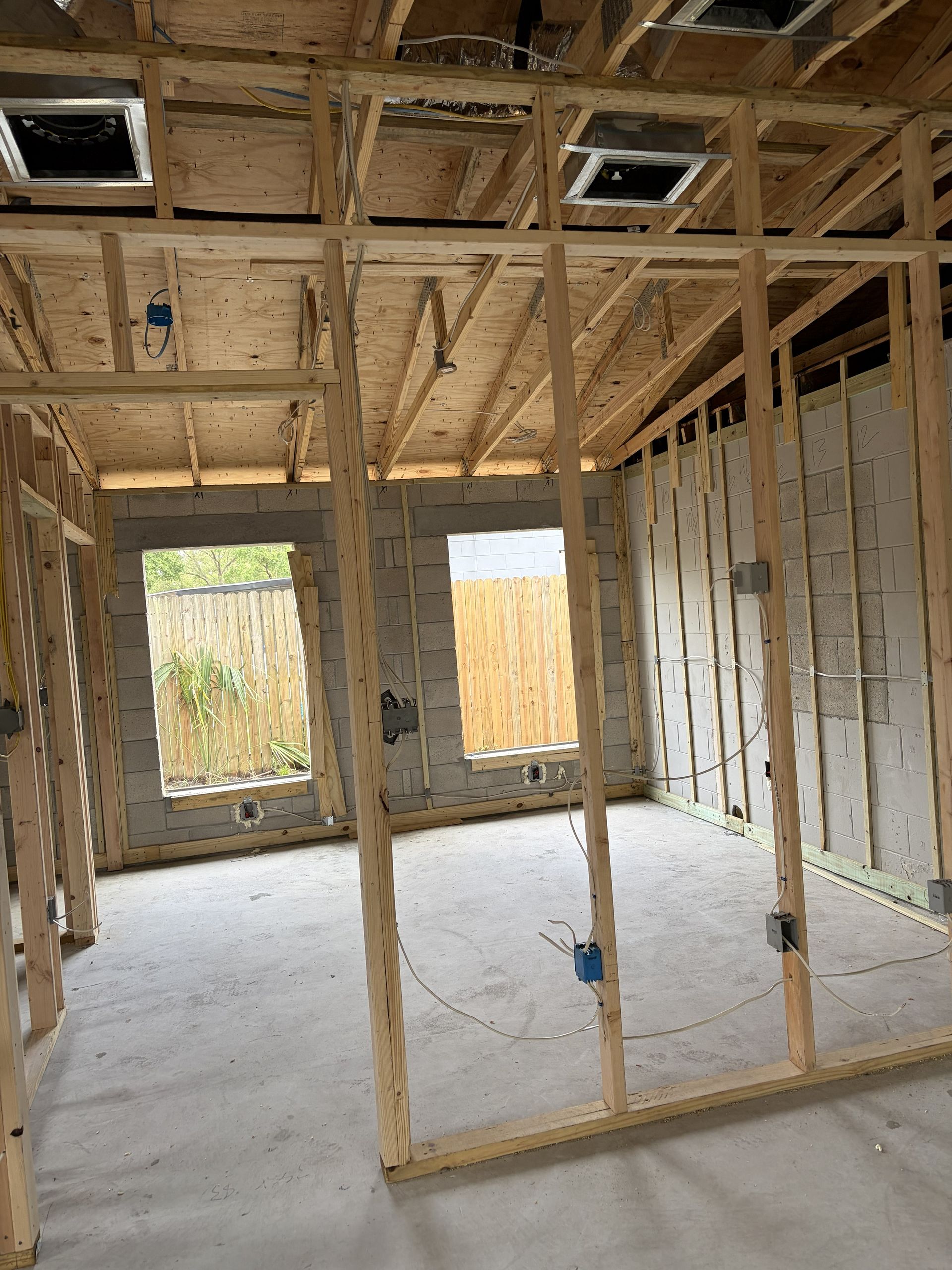 Framed interior of a house under construction with exposed wooden studs, ceiling joists, and unfinished walls