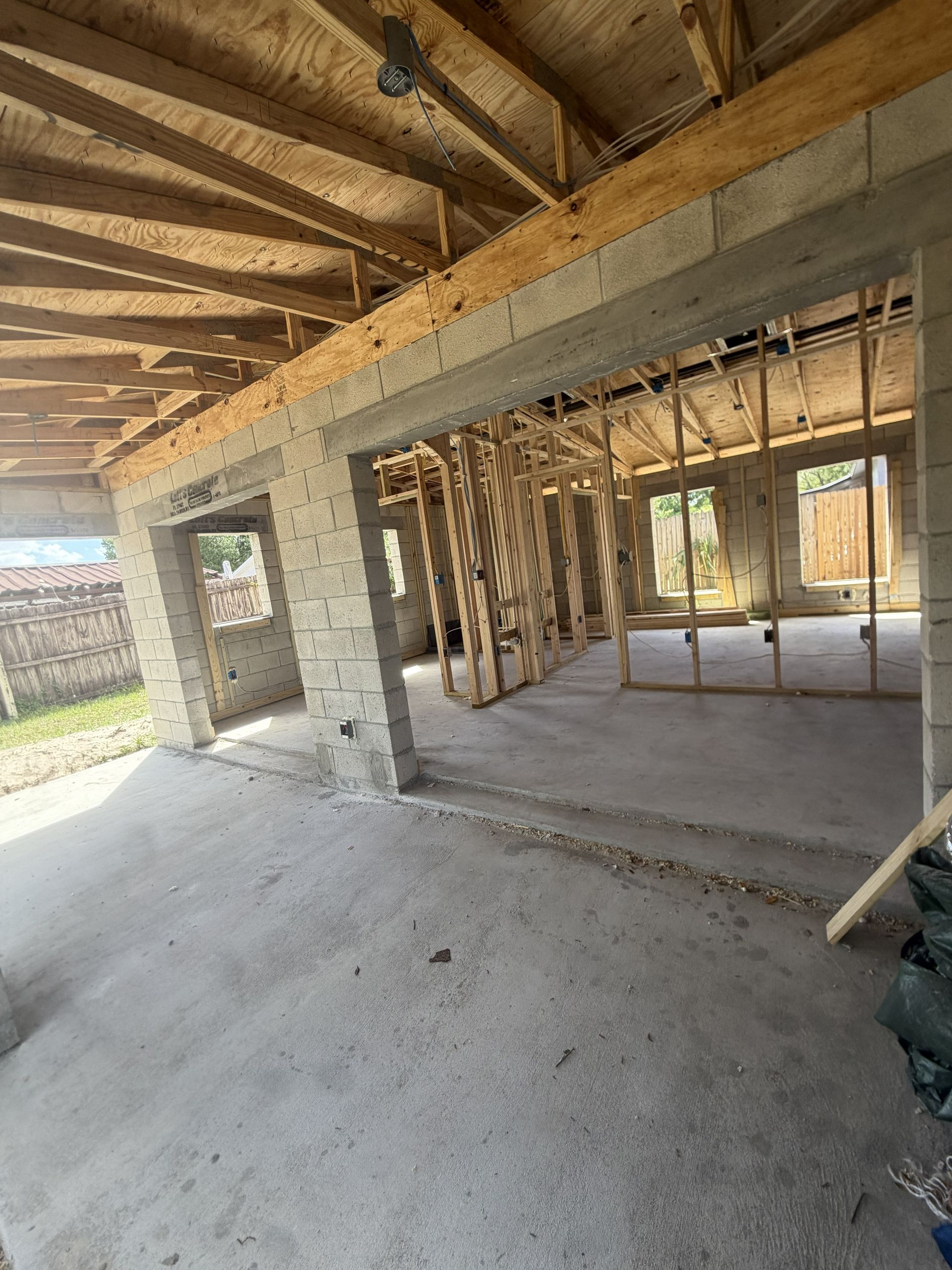Interior of an unfinished building with concrete floor, exposed beams, and framed wall openings