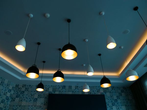 Modern ceiling with hanging pendant lights and warm cove lighting over a blue-tiled wall