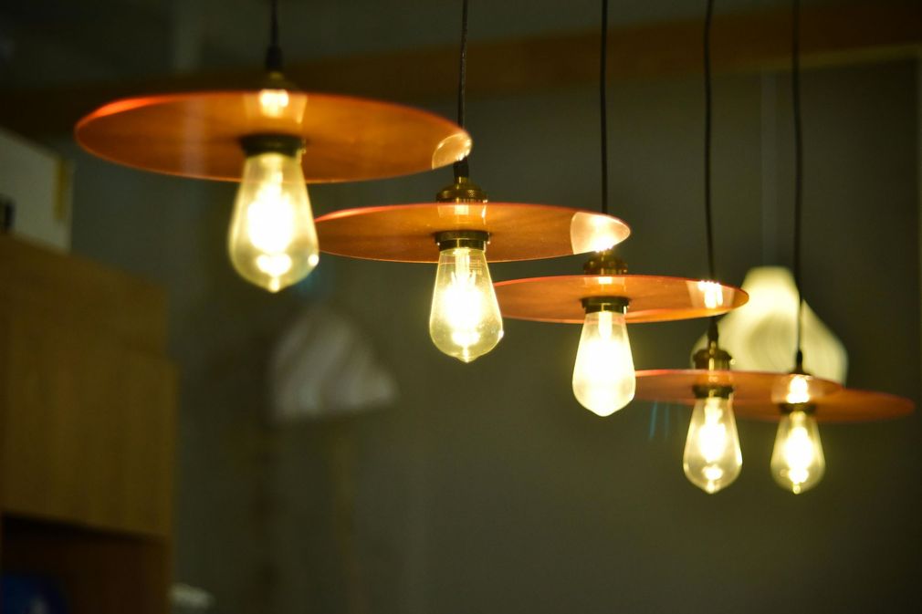 Four glowing pendant lights with copper shades hanging in a row indoors