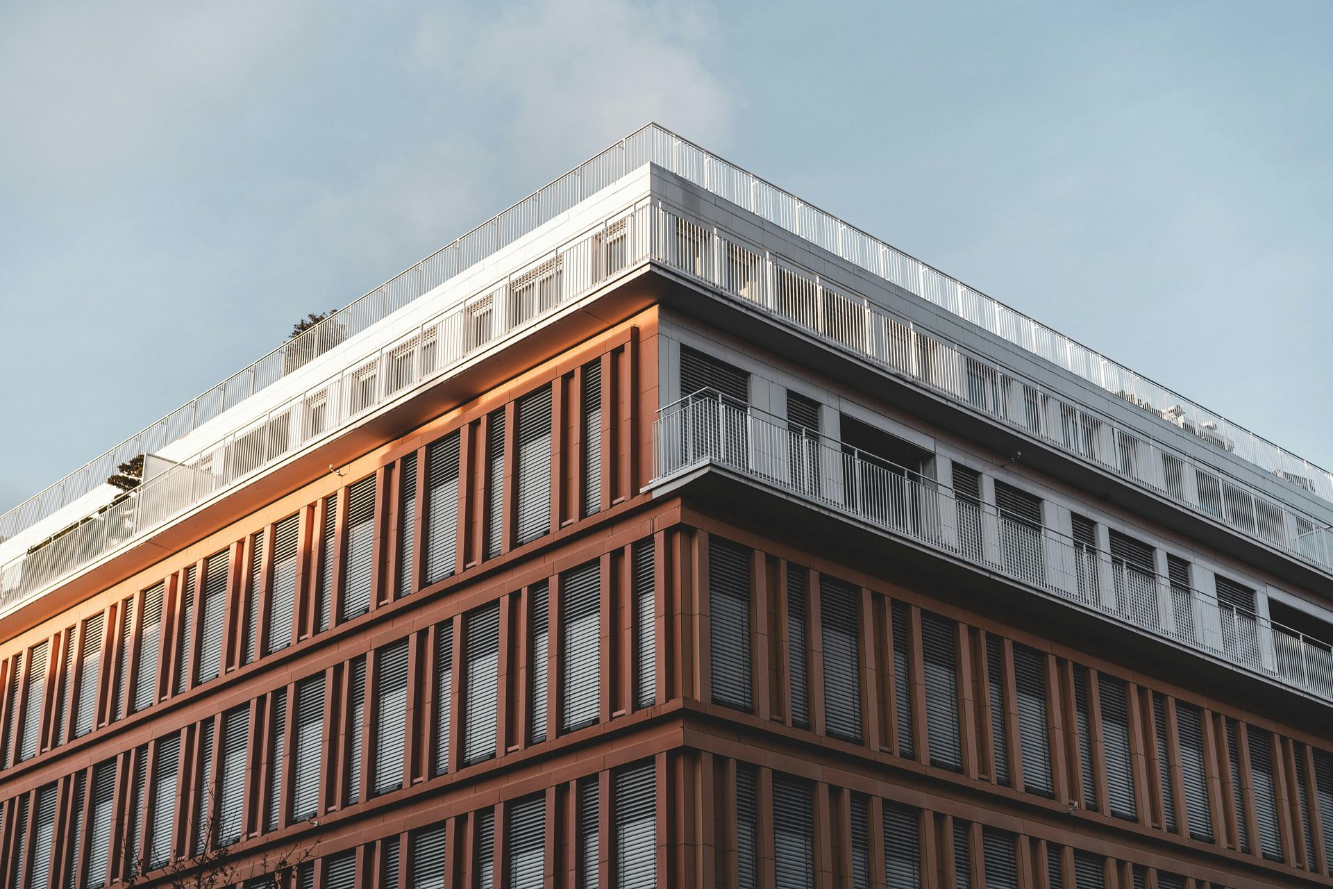 The corner of a large building with a balcony on top of it.