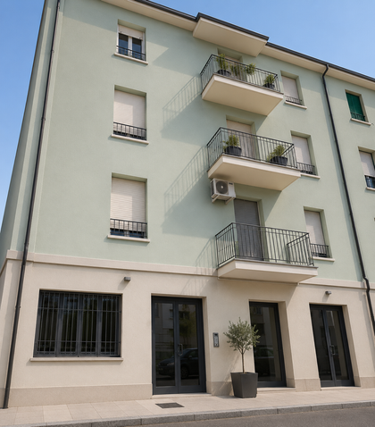 Facciata di un condominio con balconi, pareti bianche e ingresso in vetro al piano terra.