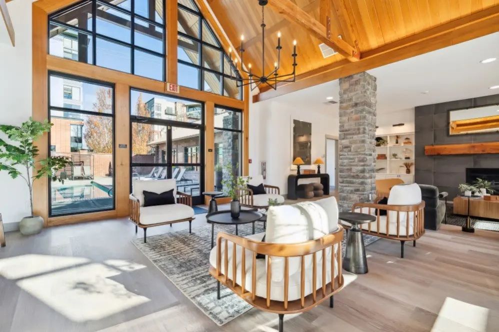 Lounge area with large windows, wooden ceiling, stone pillar, and modern furniture.