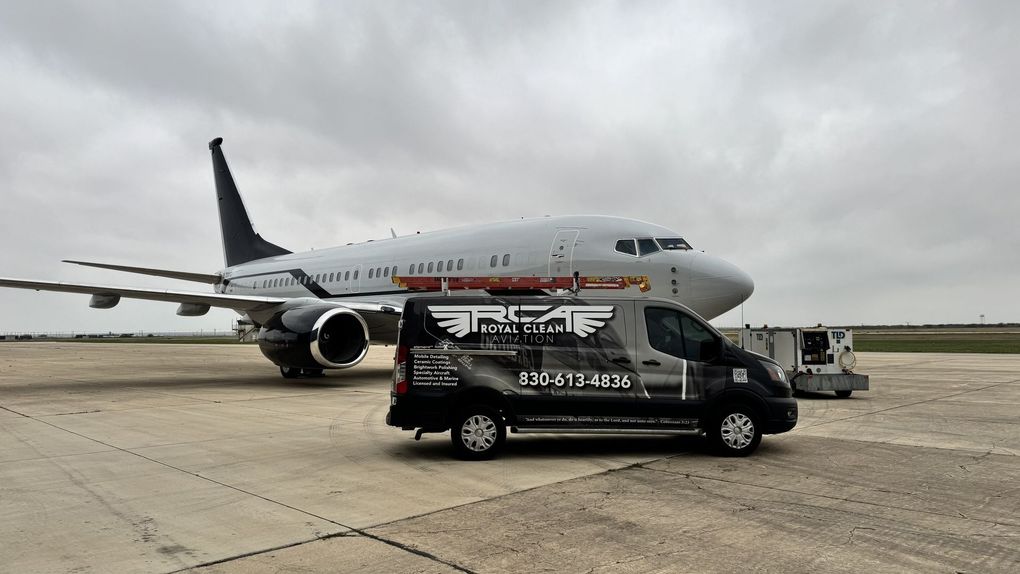 Black shuttle van parked before a commercial airplane on an airport tarmac