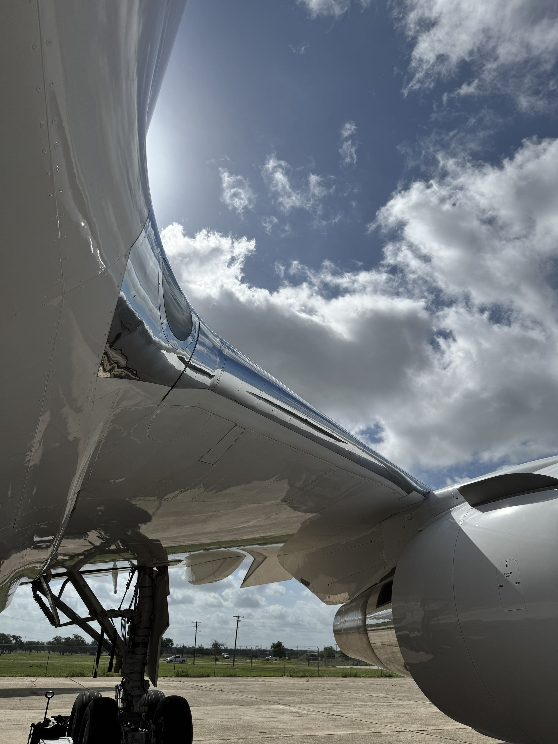 Close-up of a white airplane wing and engine against a cloudy sky on the tarmac