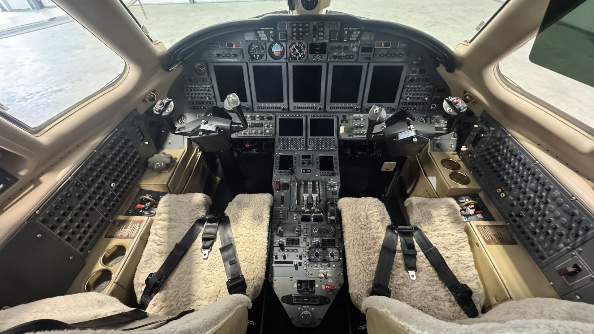 Empty airplane cockpit interior with pilot seats, control panels, and sunlight through the windows