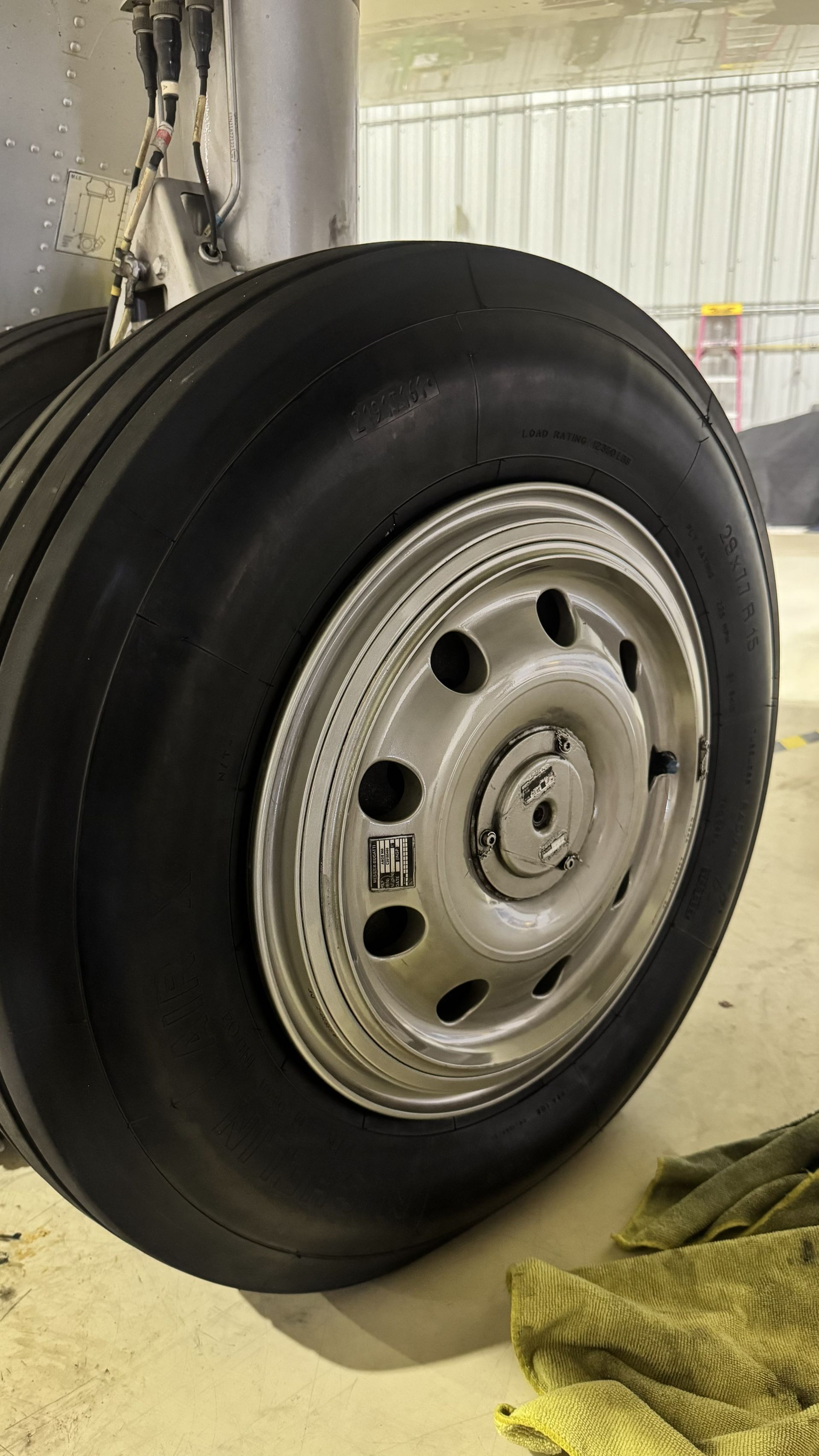 Close-up of a black tire mounted on a silver wheel in a garage or workshop.