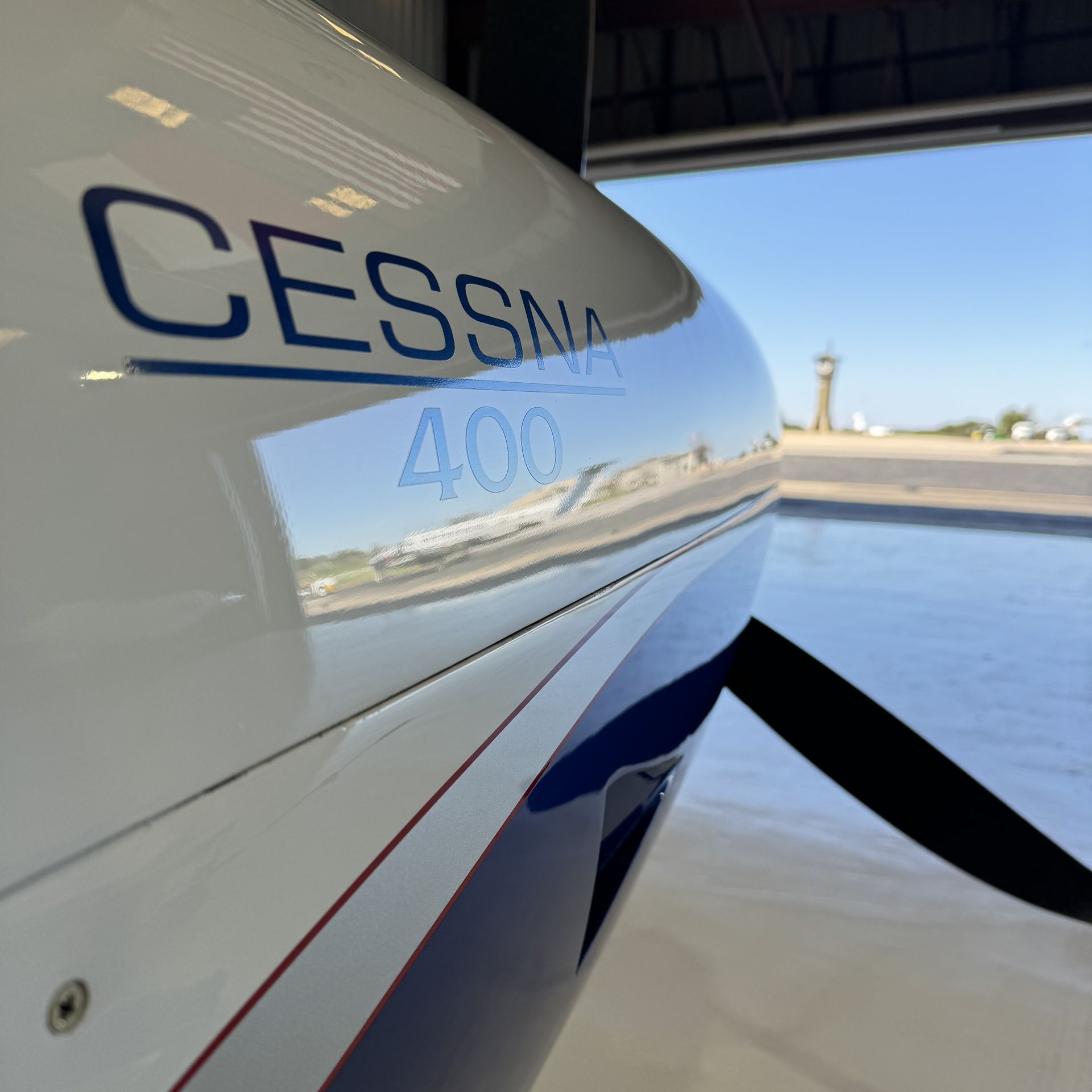 Close-up of a Cessna 400 airplane on a runway, with hangar and sky in the background