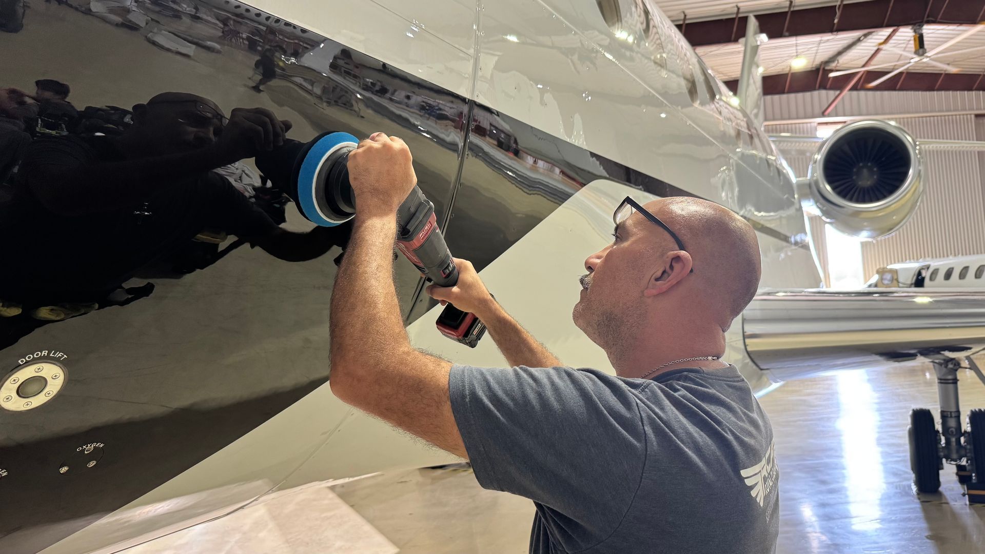 Man polishing the black nose of a jet in a hangar