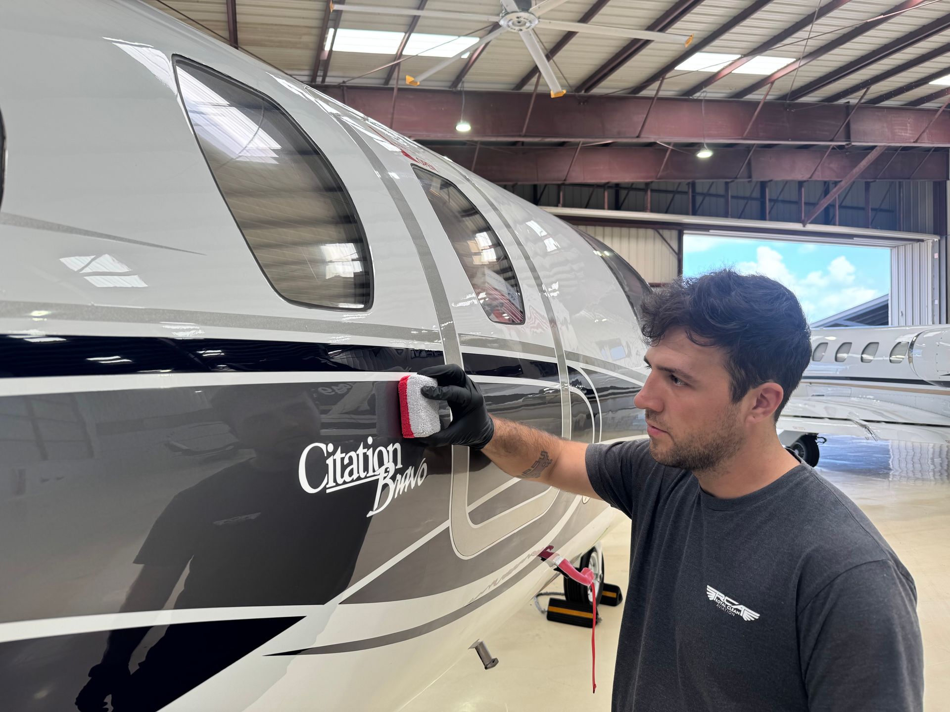 Man inspecting a white-and-black airplane in a hangar, touching the fuselage near the cockpit.