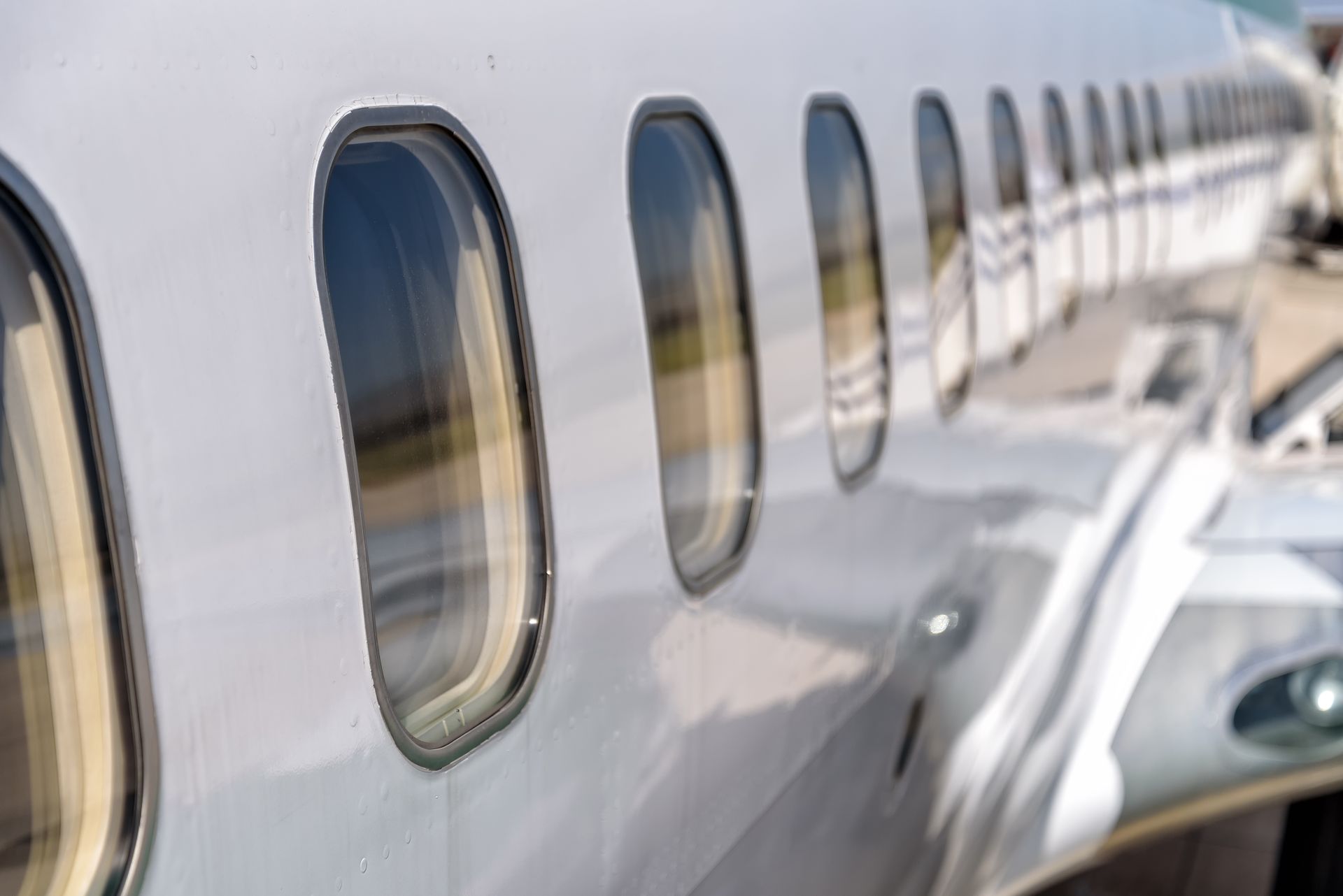 Row of airplane windows on a white passenger jet, seen from the side on the tarmac