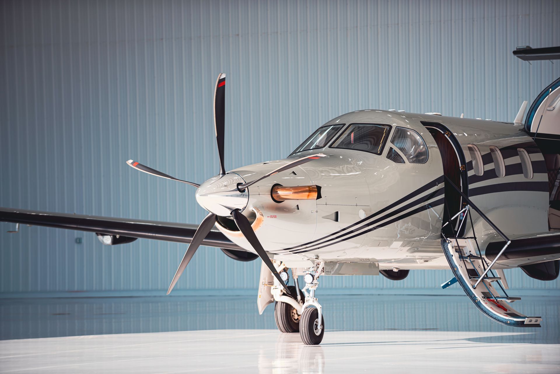 Small single-engine propeller airplane in a hangar, viewed from the front-left side.