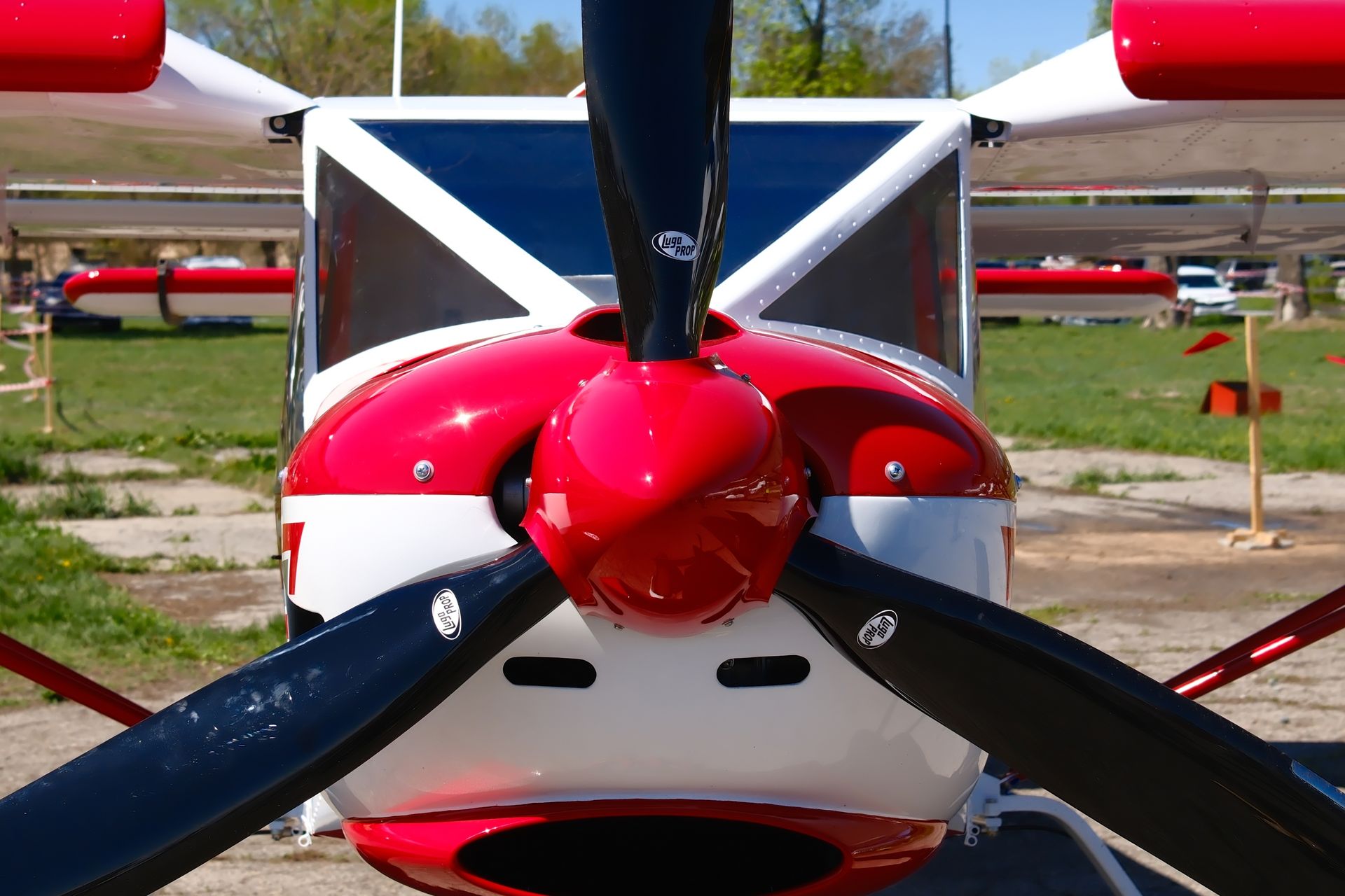 Close-up of a red and white propeller airplane nose and spinning black propeller on a runway