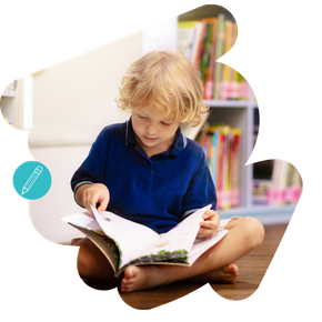 Een kind leest een boek terwijl het met gekruiste benen op de grond zit in een omgeving die op een bibliotheek lijkt.