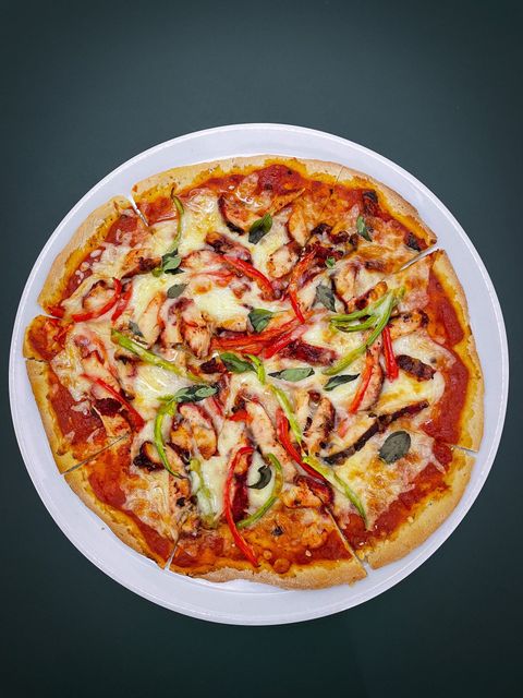 Overhead view of a vegetable pizza on a white plate against a dark background