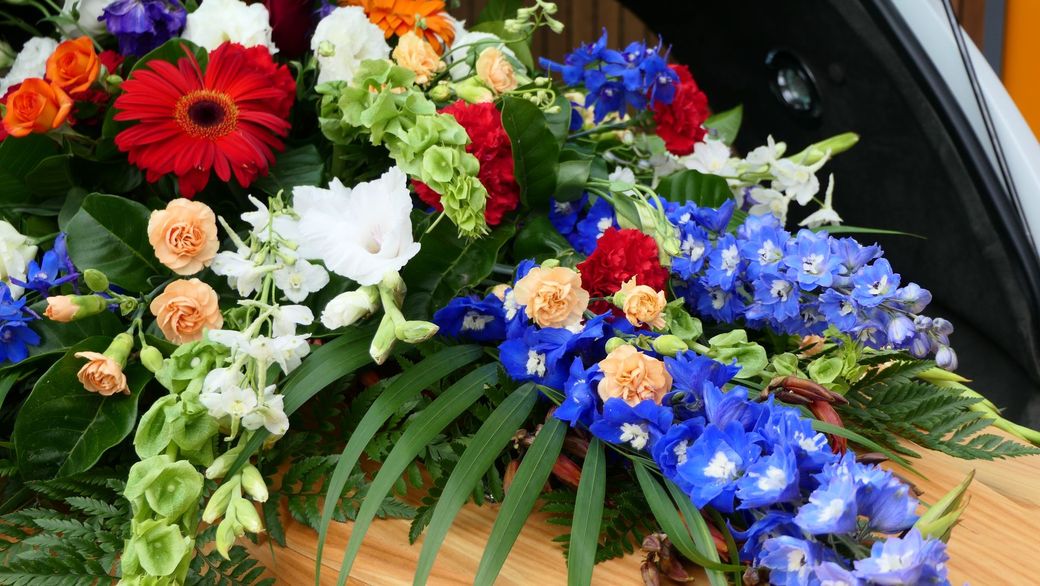 Una bara ricoperta di fiori è posizionata sul retro di un'auto.