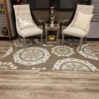 Two cream chairs flanking a small fireplace on a patterned rug in a living room