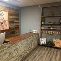 Small shop counter with stone front, wooden shelves, and CBD product displays.