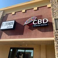 Storefront signs for “EXTENDS salon” and “CBD American Shaman” on a tan building