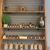 Wooden shelf with apothecary-style bottles, a potted plant, and decor in a rustic shop display
