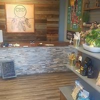 CBD shop counter with wooden walls, display shelves, and potted plants in a warm interior