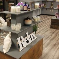 Relax sign on a gray counter in a spa lounge with candles and shelves of products.