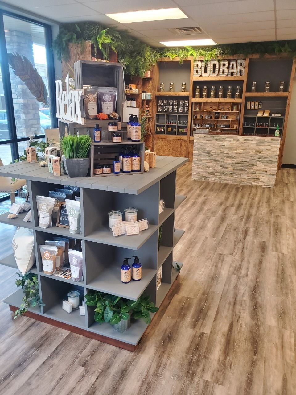 Bright retail shop interior with wooden floors, display shelves, and a counter of products and plants