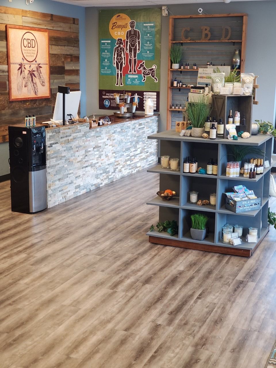 Modern café interior with stone counter, wood floors, wall art, and a display shelf of products