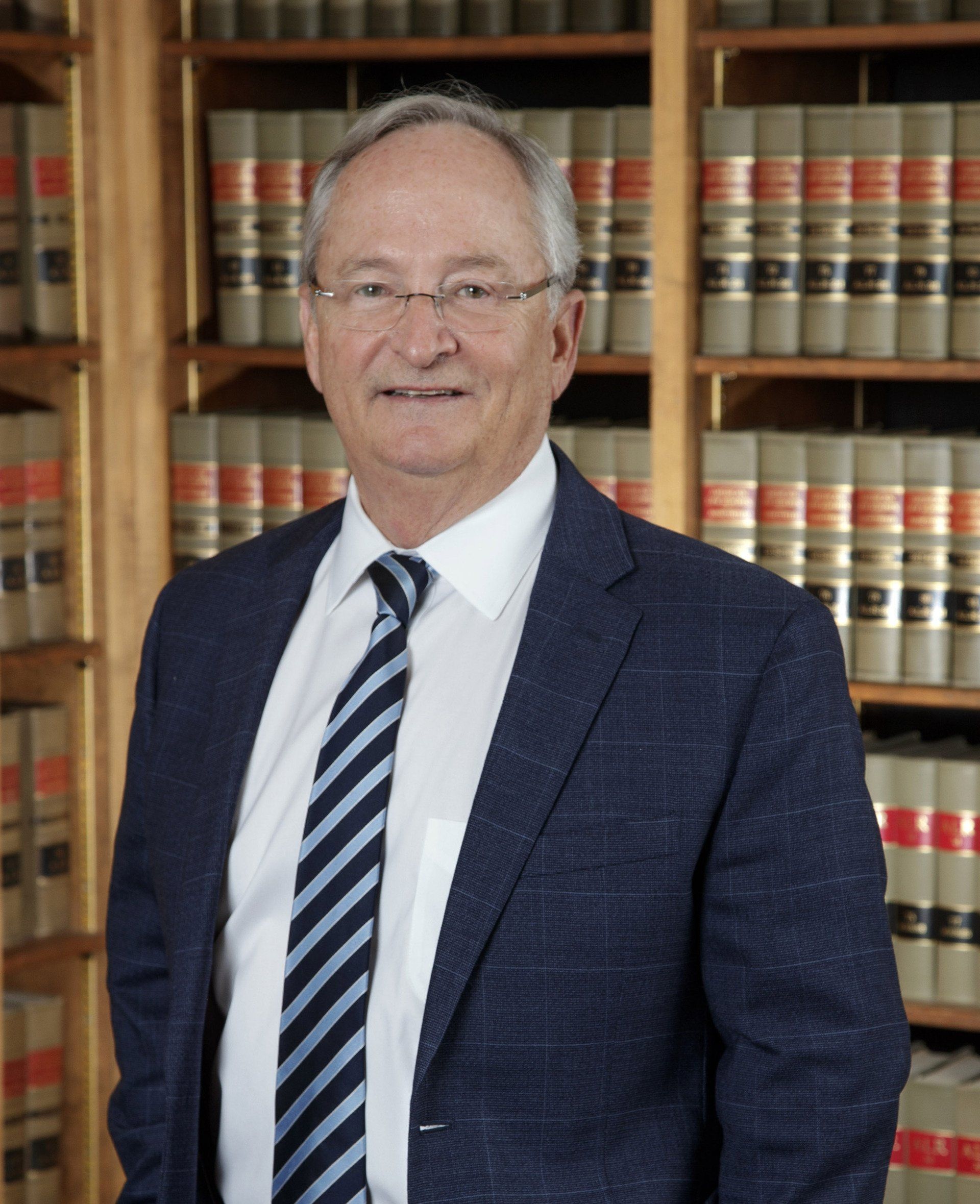 A man in a suit and tie is standing in front of a bookshelf