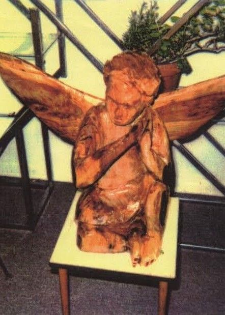 Carved wooden angel sculpture with outstretched wings on a small table indoors