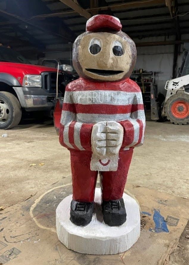 Painted statue of a toy soldier in red-and-white stripes standing indoors on a concrete floor.