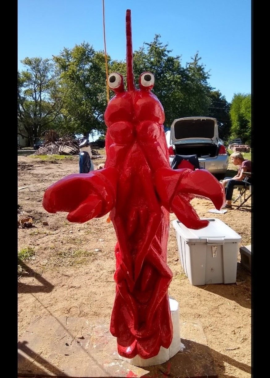 Person in a red lobster costume standing outdoors at a sunny event area.