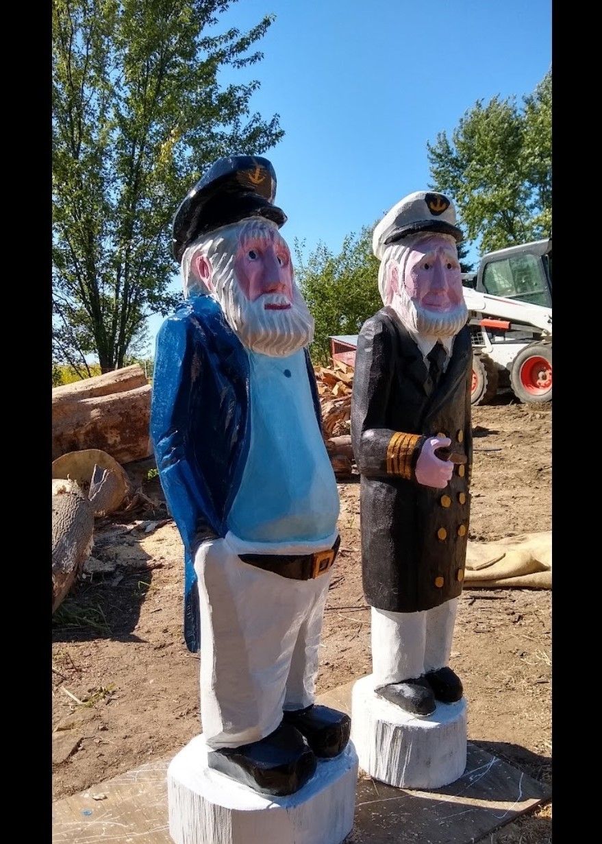 Two colorful pirate statues standing outdoors in a sunny park.
