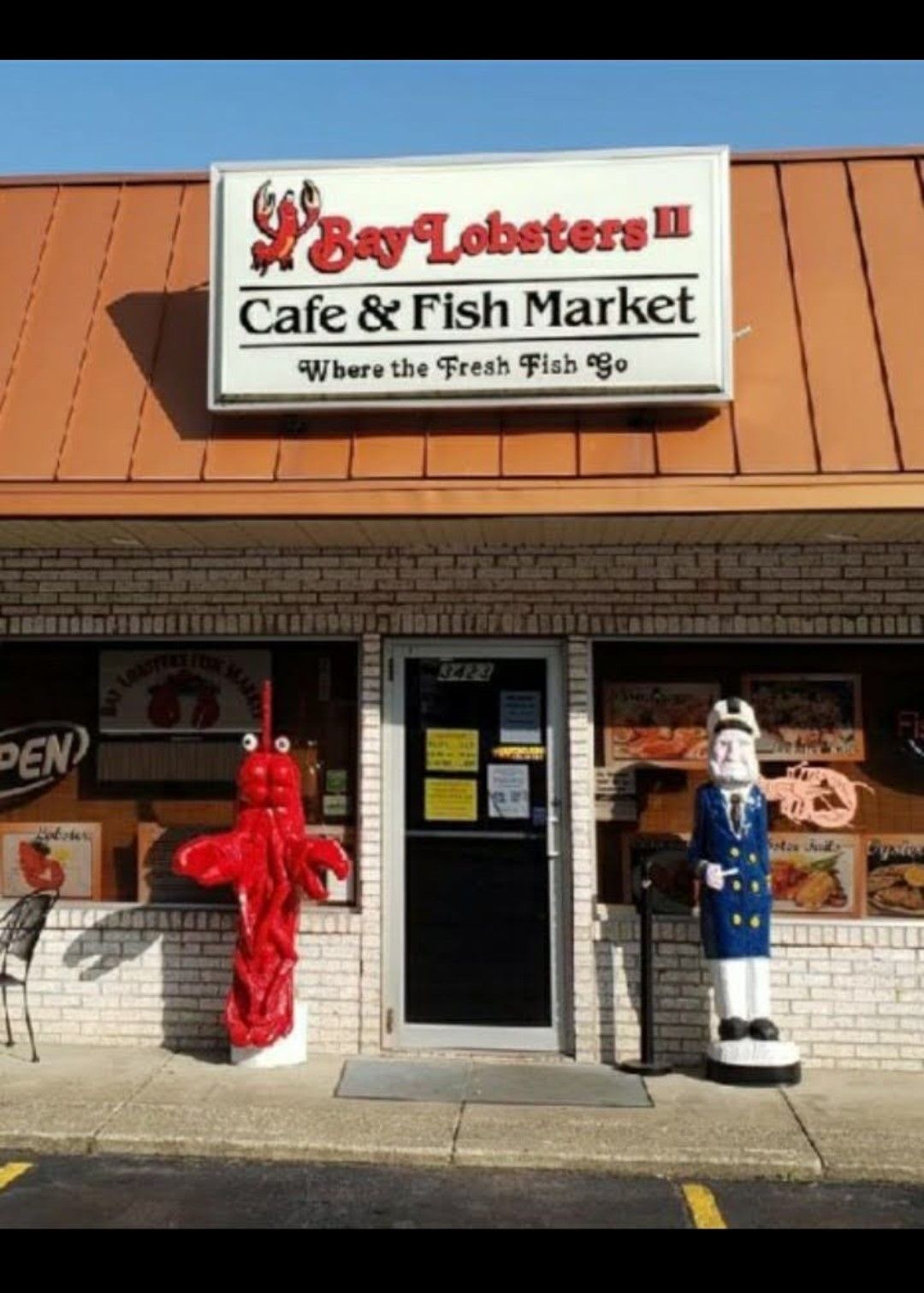 Bay Lobsters Cafe & Fish Market storefront with red lobster statue and blue sailor figure