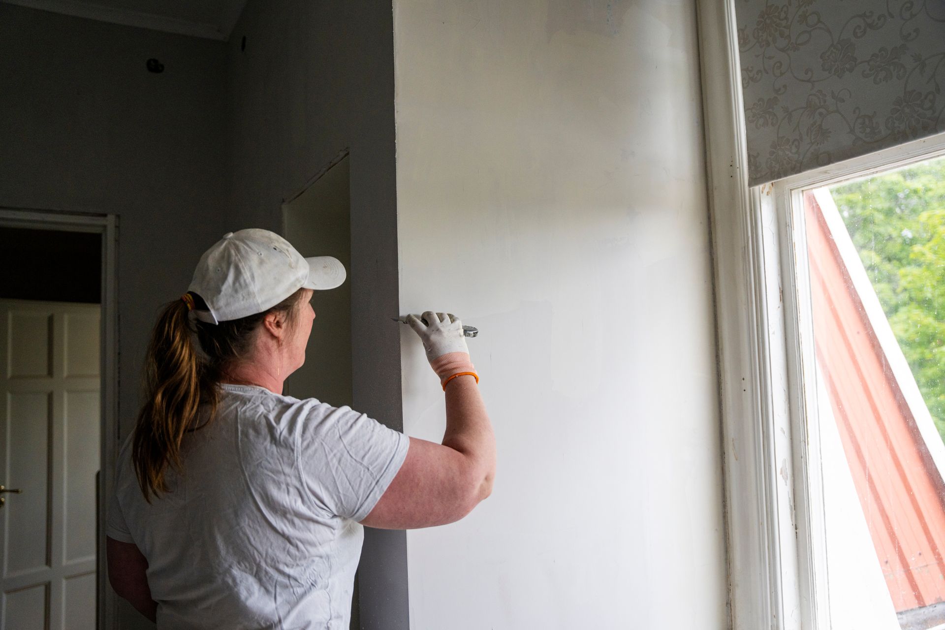 Rear view of female repairperson plastering wall at a site. Rear view of female repairperson plastering wall at a site.