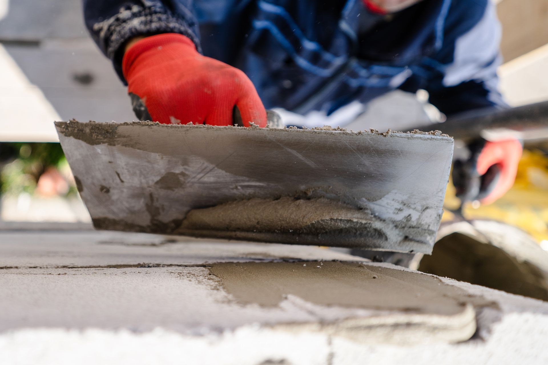 A construction worker plastering a wall outdoors with trowel cement mortar. He is holding a tool. A construction worker plastering a wall outdoors with trowel cement mortar. He is holding a tool.