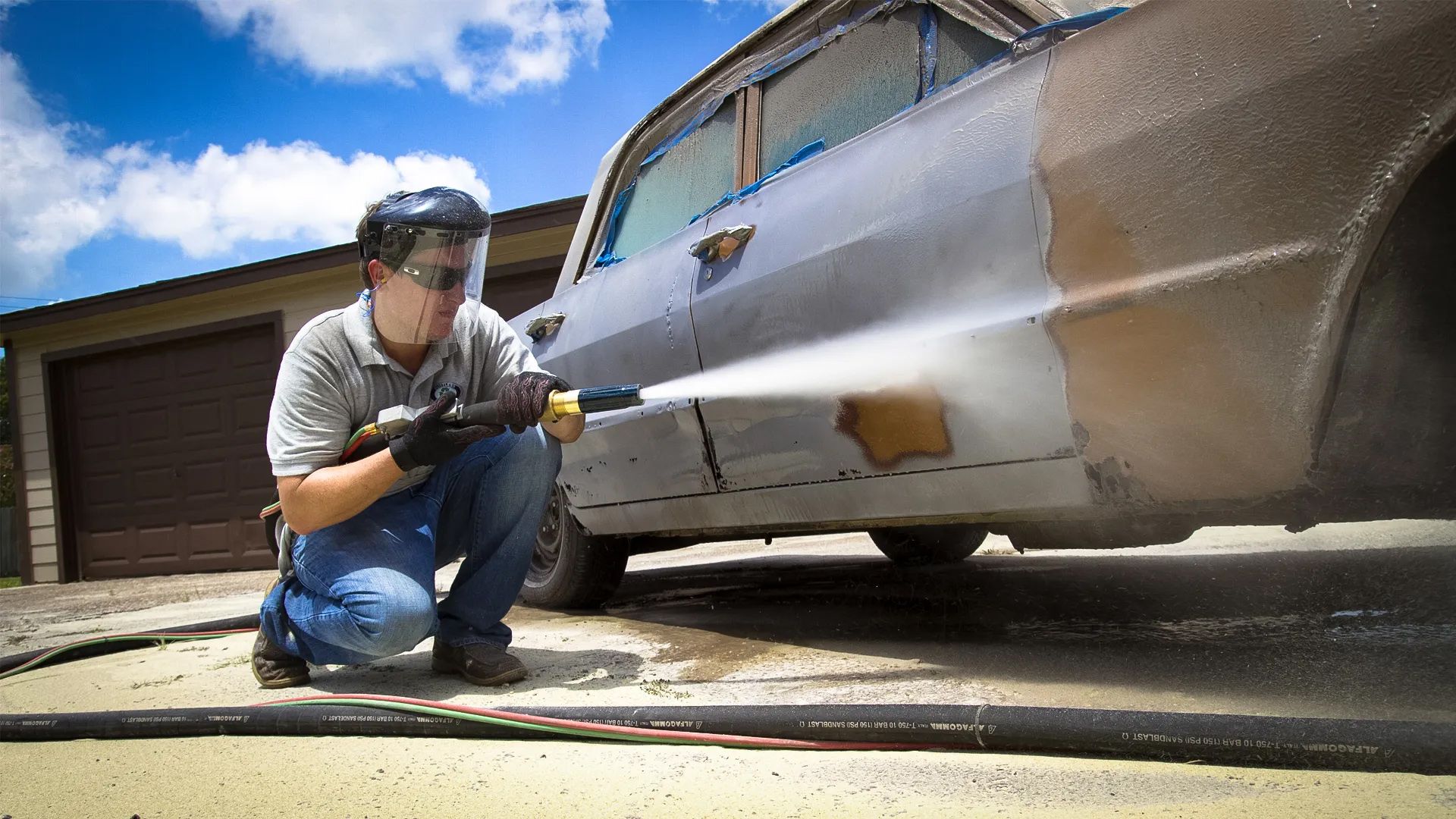 A man is cleaning a car with a high pressure washer.