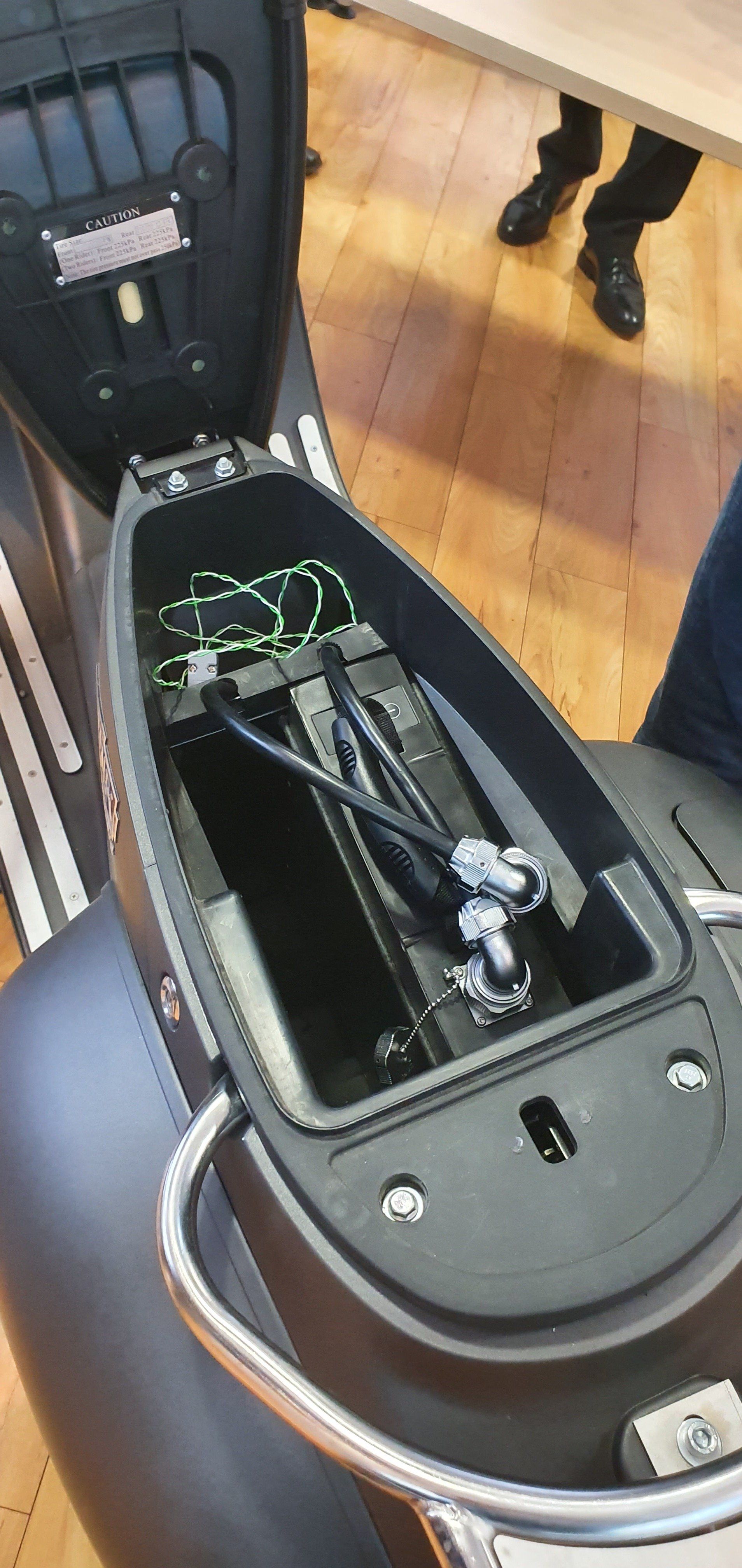 The trunk of an electric scooter with a battery in it.