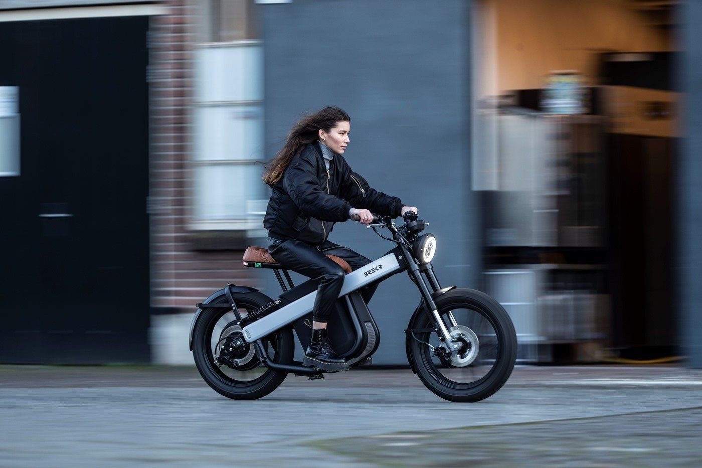 A woman is riding an electric motorcycle on a city street.