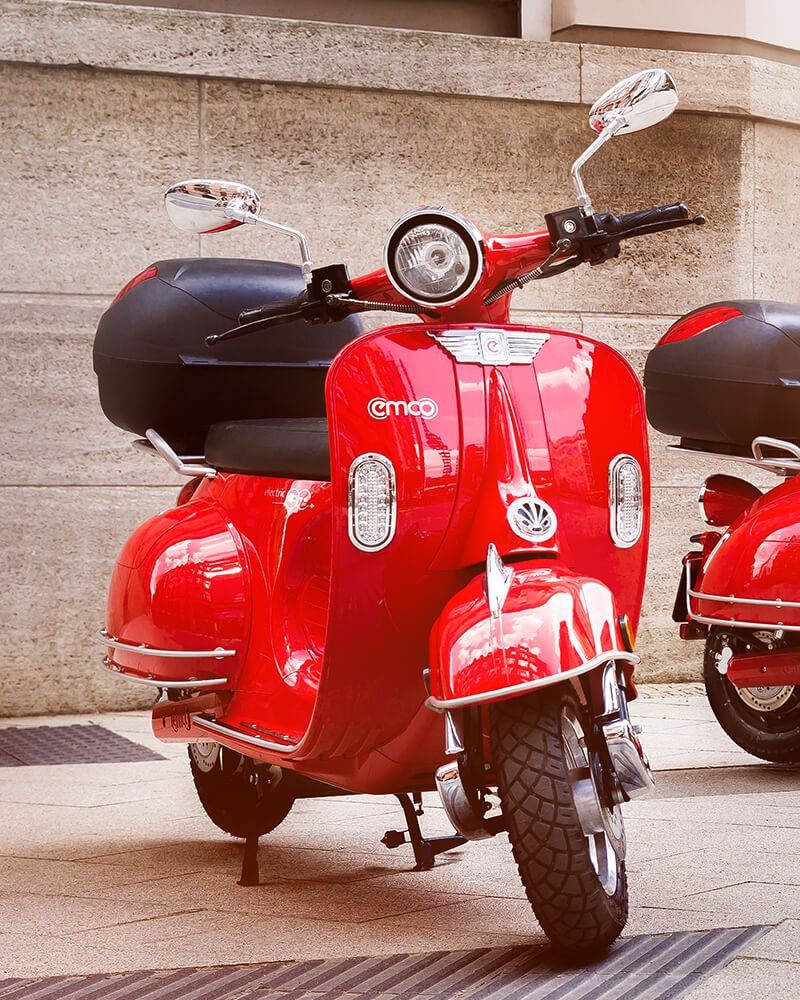 Two red scooters are parked in front of a building