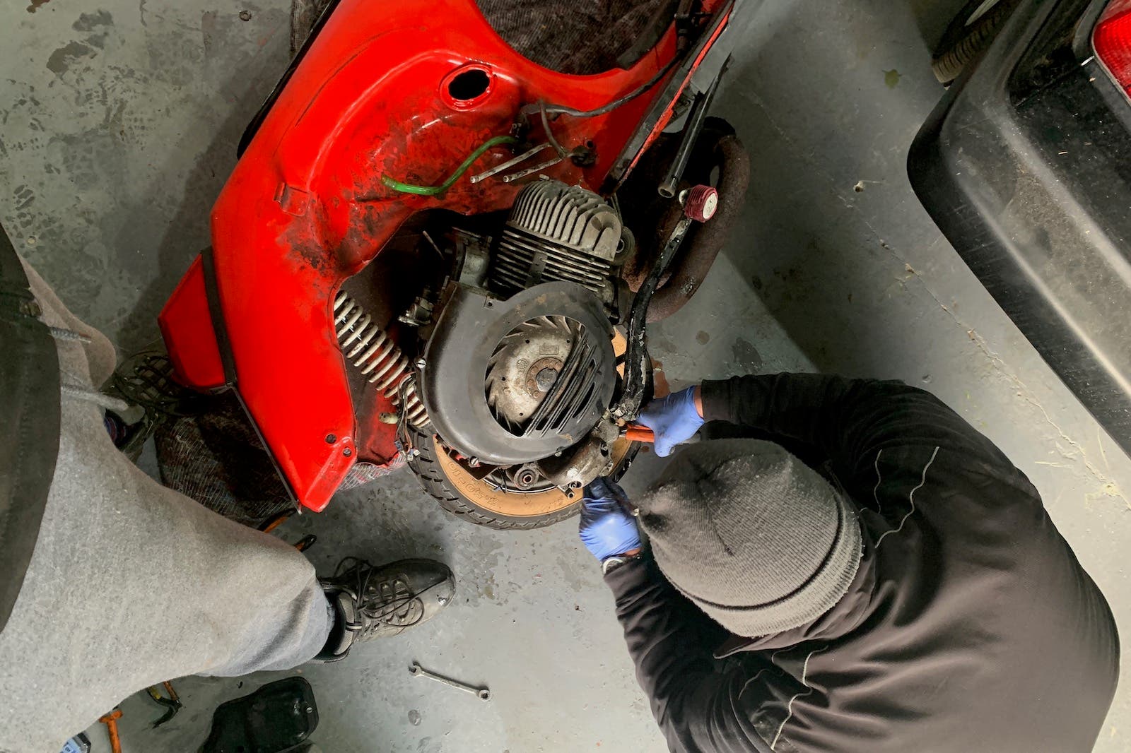 A man is working on a red lawn mower in a garage.